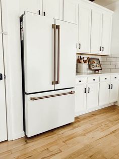 a white refrigerator freezer sitting inside of a kitchen next to wooden floors and cabinets