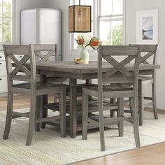 a dining room table with six chairs and a vase on top of it in front of a refrigerator