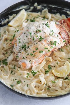 lobster and pasta in a skillet with lemon wedges