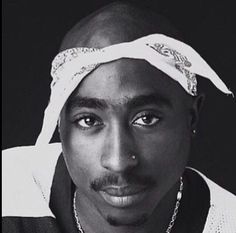 a black and white photo of a man with a bandanna on his head wearing a necklace