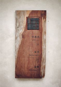 a piece of wood with writing on it and a window in the top half that is missing