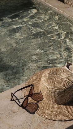 a hat and sunglasses sitting on the edge of a pool