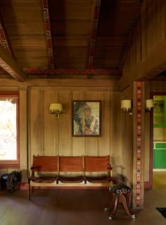 a room with wood paneling and paintings on the wall, two benches in front of them