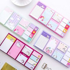 several unicorn themed notepads and binders on a white table with a cup of coffee