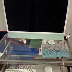 a computer monitor sitting on top of a glass desk next to a keyboard and mouse