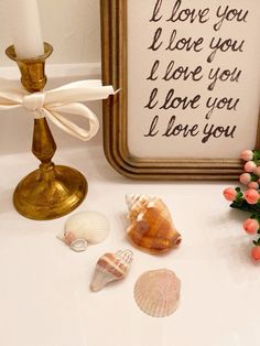 seashells and candles are on the table next to a framed love you sign