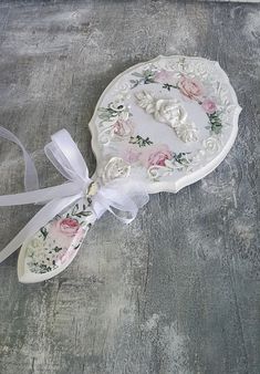 a white plate with flowers on it and a ribbon tied around the edge is sitting on a wooden surface