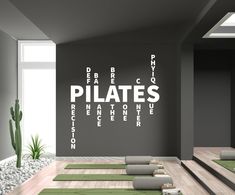 yoga mats lined up in front of a wall with pilates written on it