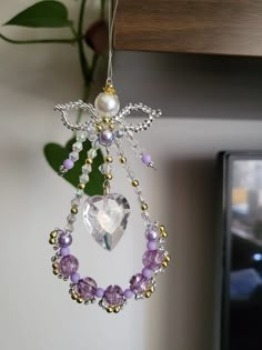 an ornament hanging from the ceiling with purple beads and crystal hearts on it