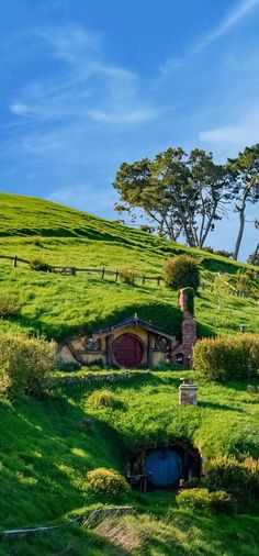 a hobbot house in the middle of a lush green field with trees on top