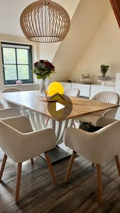 a dining room table with chairs and a vase filled with flowers sitting on top of it