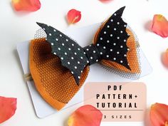 an orange and black bow with white polka dots on it, next to some flowers