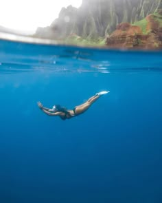 a woman swimming in the ocean with her head above water's surface and mountains behind her