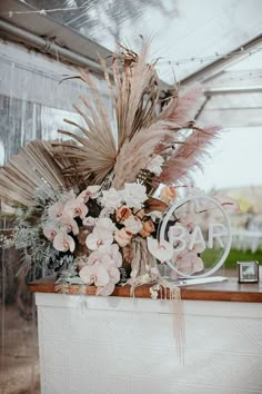 an arrangement of flowers and feathers is on display in a glass case at the reception