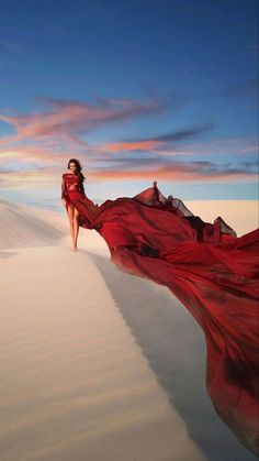 a woman in a red dress is walking across the desert