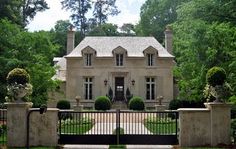 a large house with a gate in front of it and trees around the entrance area