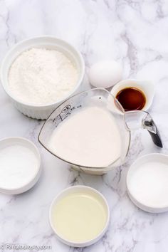 the ingredients for this recipe include eggs, milk, and flour in small white bowls on a marble countertop