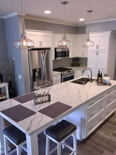 a kitchen with an island, sink and stove top oven next to two bar stools