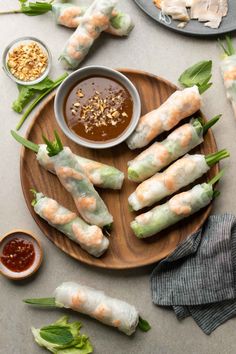 shrimp spring rolls with dipping sauce on a wooden platter next to other appetizers