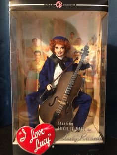 a doll in a box with a violin on it's chest and an i love lucy pin