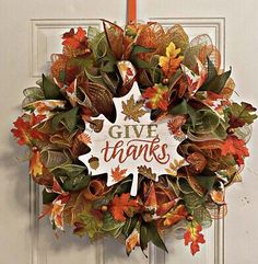 a wreath that says give thanks with autumn leaves and fall foliages on the front door