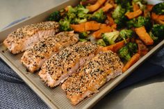 salmon, broccoli and carrots on a tray with sesame seed sprinkles