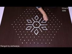 a woman is making a rangdi with white dots on the floor and using it to decorate