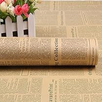 an old newspaper laying on top of a table next to flowers and a vase with roses in it