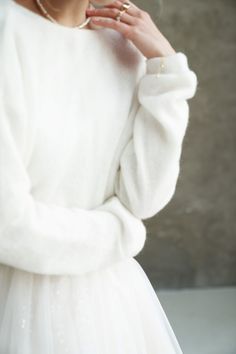 a woman in a white dress and pearls on her finger is posing for the camera