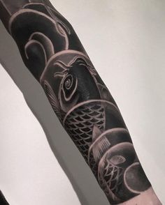 a man's arm with black and grey tattoos on it, including an image of fish