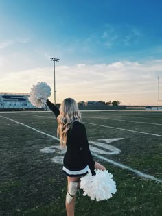 a cheerleader is on the football field with her pom poms in hand