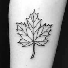 a black and white photo of a leaf tattoo on the left calf leg, with an outline of a maple leaf