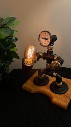 a lamp that is sitting on top of a wooden board next to a potted plant