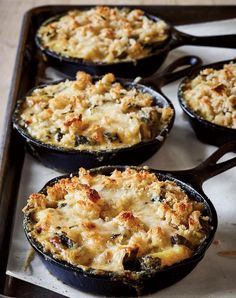 four cast iron skillets filled with food on top of a stove burner,