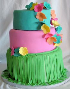 a three tiered cake decorated with flowers and fringes on a white tablecloth