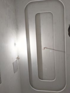 a man standing in front of a white wall next to a toilet and shower head