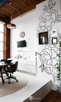 a room with a desk, chair and television on the wall next to a window