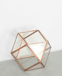 a glass vase sitting on top of a cement floor next to a white wall,