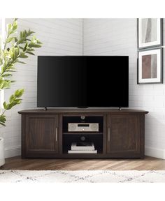 a flat screen tv sitting on top of a wooden entertainment center next to a window