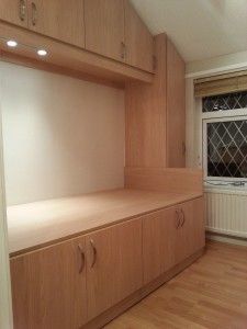 an empty room with wooden floors and cupboards on either side of the window sill