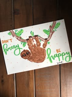 a handprinted card with a sloth hanging from a branch that says don't worry, be happy