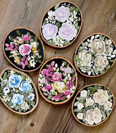 six painted wooden bowls with flowers on them sitting on a table next to each other