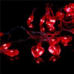 red heart shaped lights are on the black background, with one string attached to it