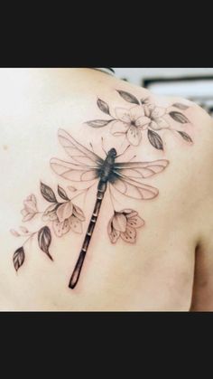 a woman's back with a dragonfly and flowers on it