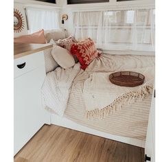 a bed with pillows and blankets on top of it next to a window in a room