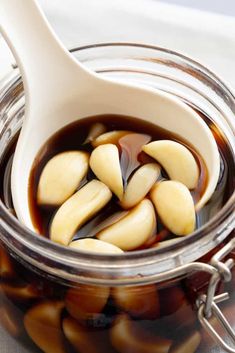 an open jar filled with jelly beans on top of a white table cloth next to a spoon