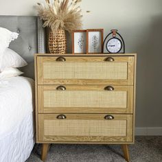 a bedroom with a bed, nightstand and clock on top of the dresser next to it