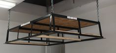 the suspended light fixture is made from metal pipes and wood planks, which are attached to chains