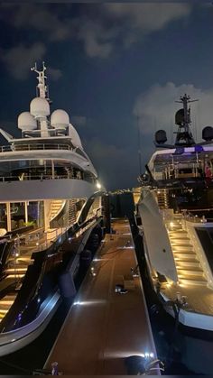 two yachts docked at night with lights on them