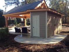 a small shed sitting in the middle of a yard with a patio and picnic table